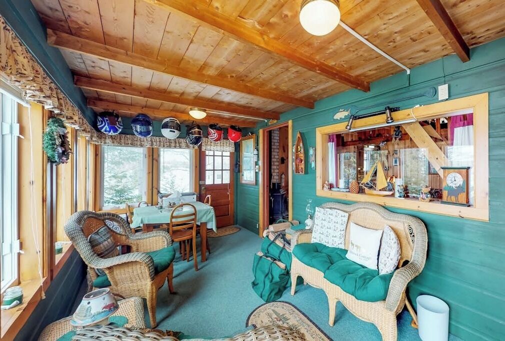 A cozy room with wicker furniture, a wooden ceiling, and a window with a view.
