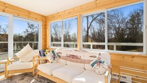 Un intérieur en bois avec un canapé, un fauteuil et de grandes fenêtres.