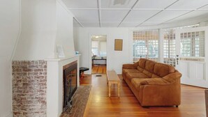 Un salón con chimenea, un sofá marrón, una mesa de centro de madera y una puerta con un cartel que dice 'Welcome'.