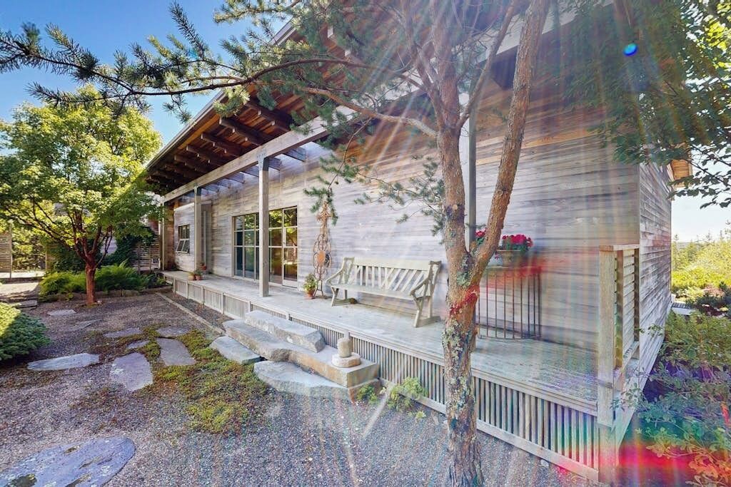 A wooden cabin with a porch, stone steps, and a garden.