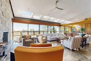 Ein großzügiger Wohnbereich mit großem Fenster, Deckenventilator und Kamin.