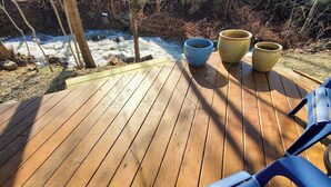 Eine Holzterrasse mit Blumentöpfen und Stühlen.