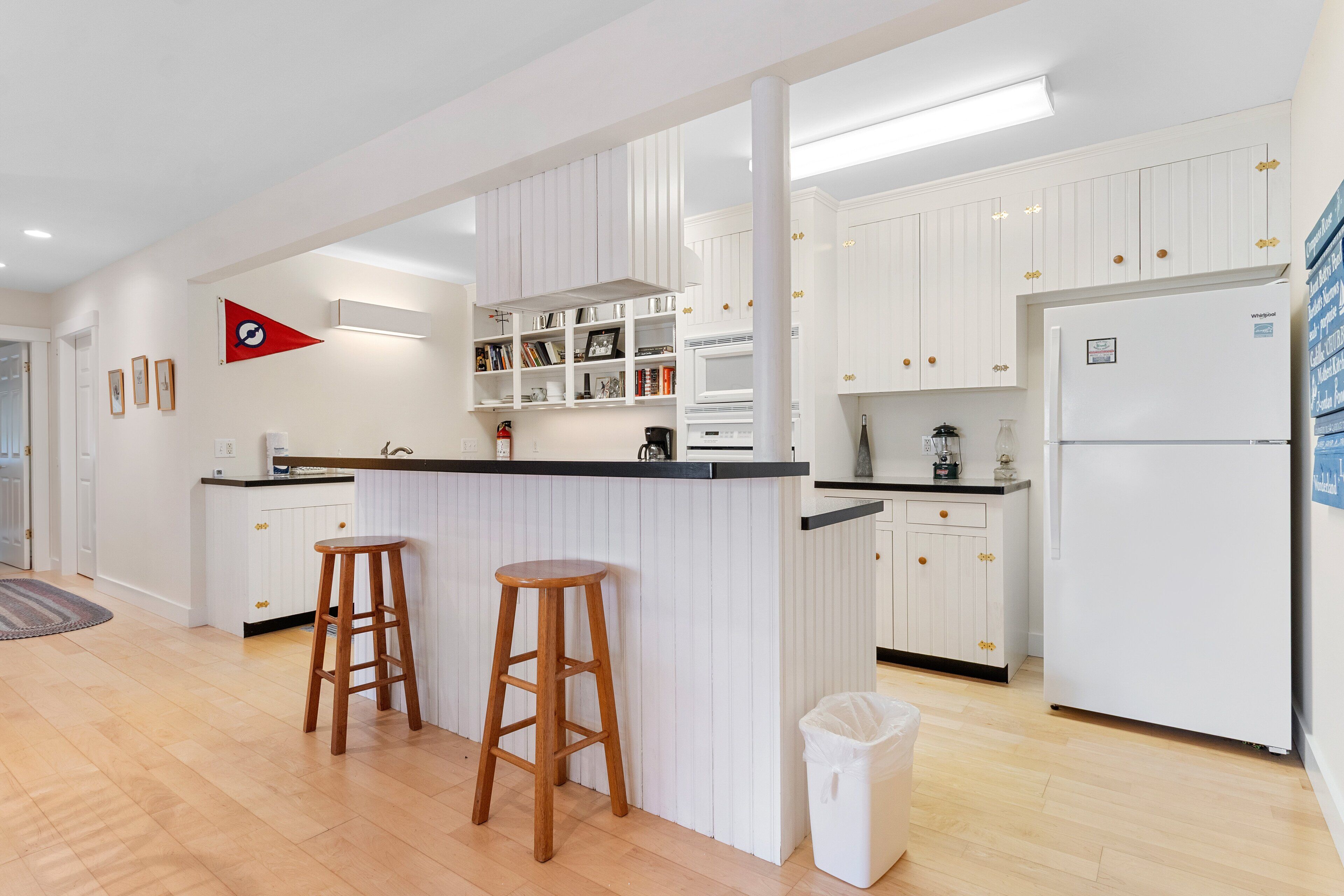A modern kitchen with white cabinetry, a central island with stools, and a refrigerator.