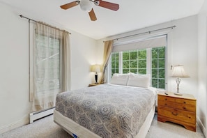 A bedroom with a bed, two bedside tables, a ceiling fan, and a window with curtains. - Convenient Home With Deck, Grill, & Washer/dryer - Walk Into Town & Acadia (Bar Harbor)