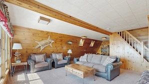 A cozy living room with a wooden ceiling, a sofa set, a coffee table, and a staircase. - Comfy Lakefront Cabin With Gorgeous Views, Private Dock & Pebble Beach (Greenville)