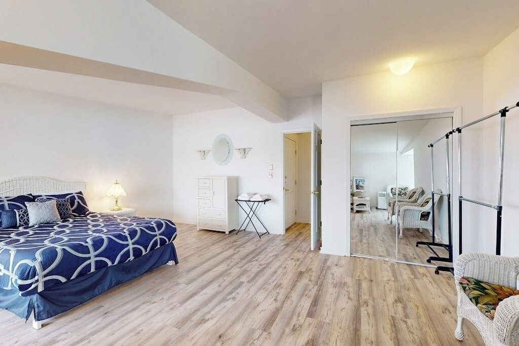 A bedroom with a bed, a dresser, a mirror, and a chair.