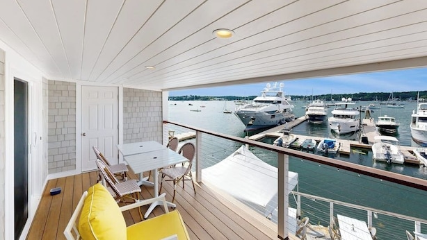 Een balkon met uitzicht op een jachthaven, een tafel met stoelen en een deur.