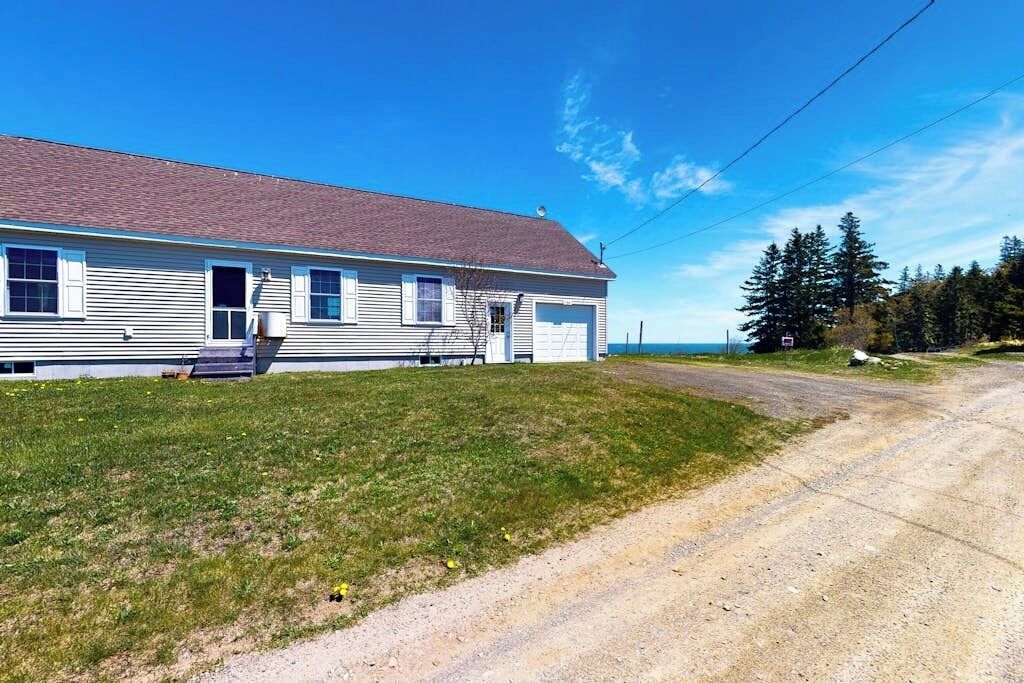 A single-story house with a front garage, a sloped roof, and a grassy yard.