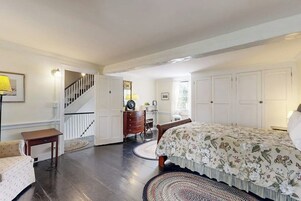 A bedroom with a bed, dresser, and a staircase.