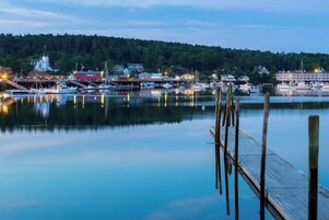 A calm harbor with boats, a dock, and buildings in the background.