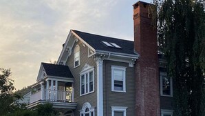 A two-story house with a stone foundation, a brick chimney, and a white picket fence. - Historic Condo in Downtown Camden, Steps to Harbor (Camden)