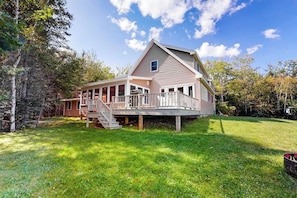 A two-story house with a deck, a covered porch, and a staircase leading to the upper level. - Dog-friendly, Bayfront Home W/rocky Beach, Full Kitchen, Washer/dryer & Firepit (Gouldsboro)