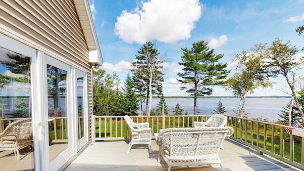 A deck with wicker furniture and a view of a lake. - Dog-friendly, Bayfront Home W/rocky Beach, Full Kitchen, Washer/dryer & Firepit (Gouldsboro)