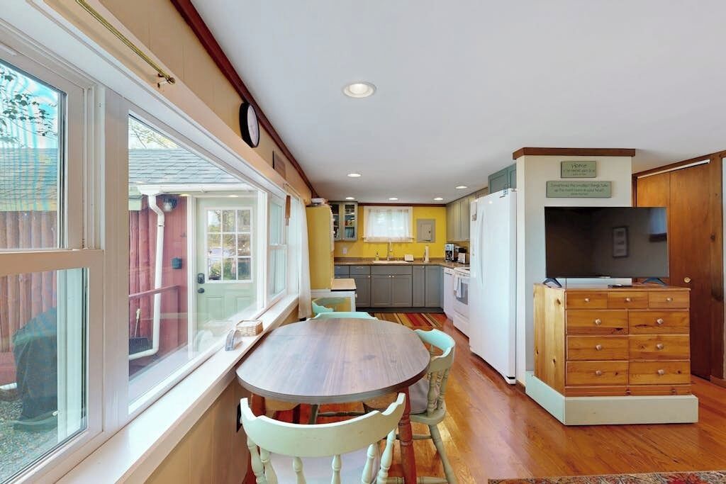 A compact kitchen with a dining area, wooden cabinets, and a built-in TV.