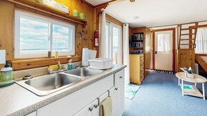 Eine Küche mit Holzausstattung, einem doppelten Spülbecken und einem Fenster mit Jalousien.