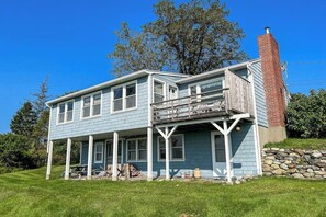 A two-story house with a balcony, a stone foundation, and a chimney.