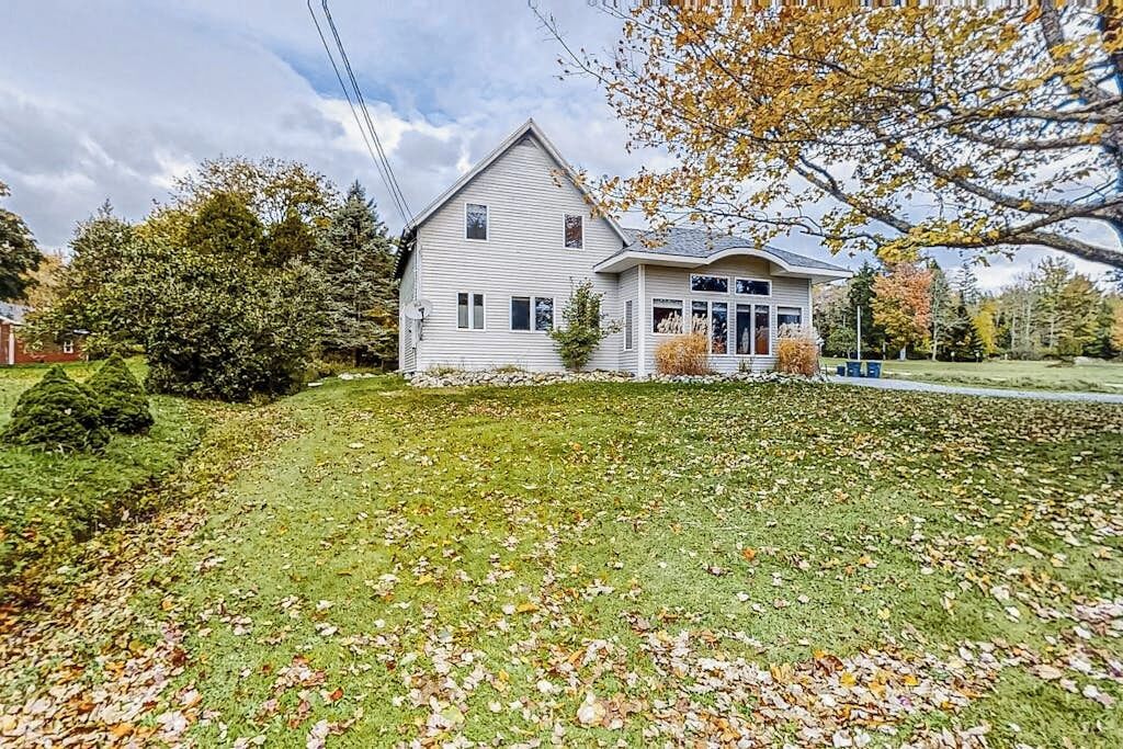 A single-story house with a sloped roof, a front porch, and a well-maintained lawn with scattered leaves.