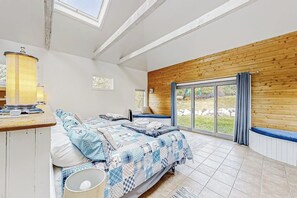 Ein Schlafzimmer mit zwei Betten, einer Holzwand, einem großen Fenster und einem Oberlicht.