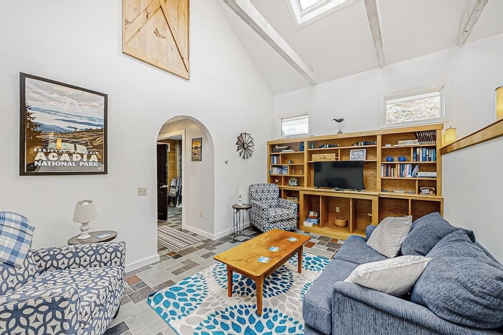 A living room with a sofa, a coffee table, a bookshelf, a TV, and a framed picture on the wall.