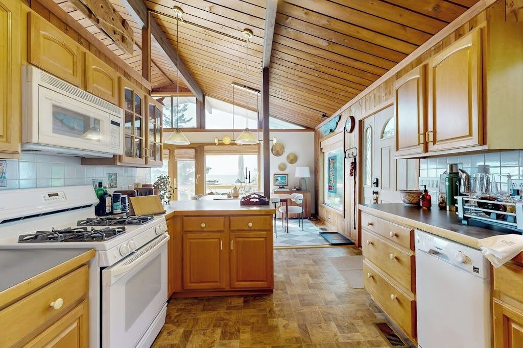 A kitchen with wooden cabinets, a central island, and a view to the dining area.