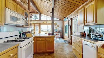A kitchen with wooden cabinets, a central island, and a view to the dining area.