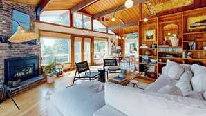 Ein geräumiges Wohnzimmer mit Kamin, Holzboden und großen Fenstern.