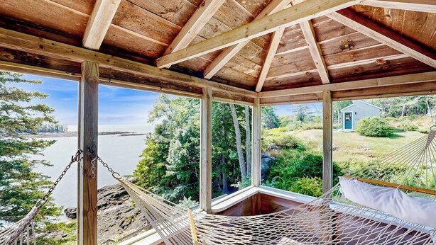 Eine Holzbalkendecke mit einer Hängematte und einem Fenster mit Blick auf eine natürliche Landschaft.