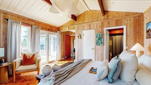 Ein Zimmer mit Holzwandverkleidung, einem Bett, einem Sessel und einem Tisch.