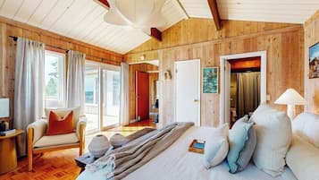 A wooden-paneled room with a bed, a chair, and a table.