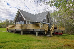 Eine Hütte mit einem geneigten Dach, einer Holzterrasse und einer Treppe, die zu einer zweiten Ebene führt.