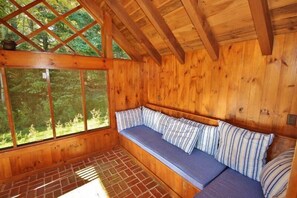 A wooden cabin interior with a built-in bench and large windows. - Tideriver, Waterfront Cottage in Maine (Port Clyde)