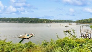 A calm river with boats, a dock, and a forested shoreline. - Charming Oceanfront Home With Stunning Water Views and Wifi (Georgetown)