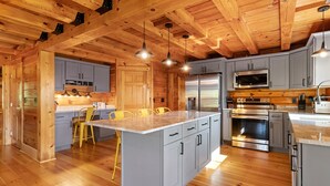Una cucina moderna con travi in legno, mobili grigi, un'isola centrale ed elettrodomestici in acciaio inossidabile.