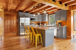 Una cocina con vigas de madera, electrodomésticos de acero inoxidable y una isla central con taburetes de bar.