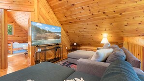L'interno accogliente di un rifugio con televisione, divano e vista su un paesaggio roccioso.