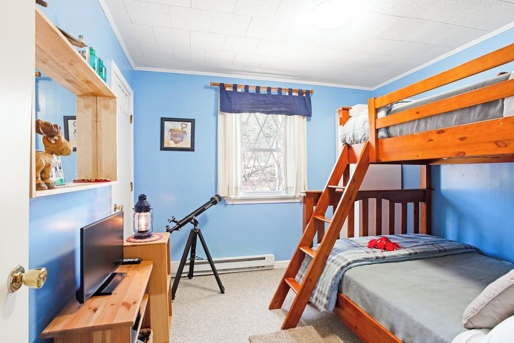Une chambre avec un lit superposé, un télescope, un bureau et une fenêtre.