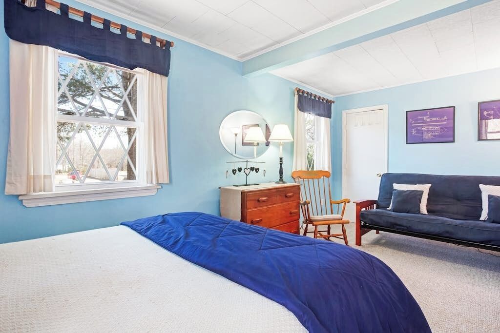 Un dormitorio con cama, cómoda, silla y sofá.