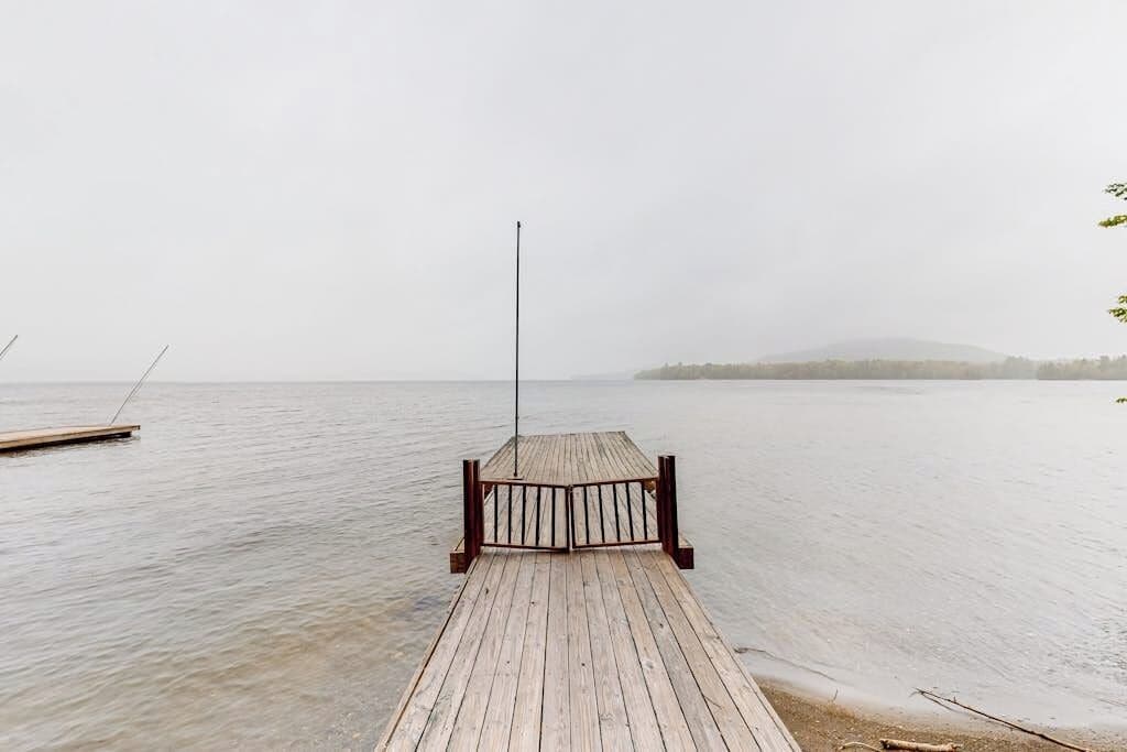 A wooden pier extending into calm water with a metal railing at the end.