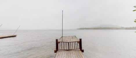 A wooden pier extending into calm water with a metal railing at the end.