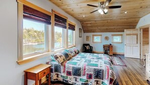 A bedroom with a wooden ceiling, a bed with a quilt, a desk, and a chair. - Charming Riverfront Home With Mountain Views & Private Dock (Rockwood)