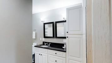 A bathroom with a double sink, white cabinetry, and two wall-mounted mirrors.