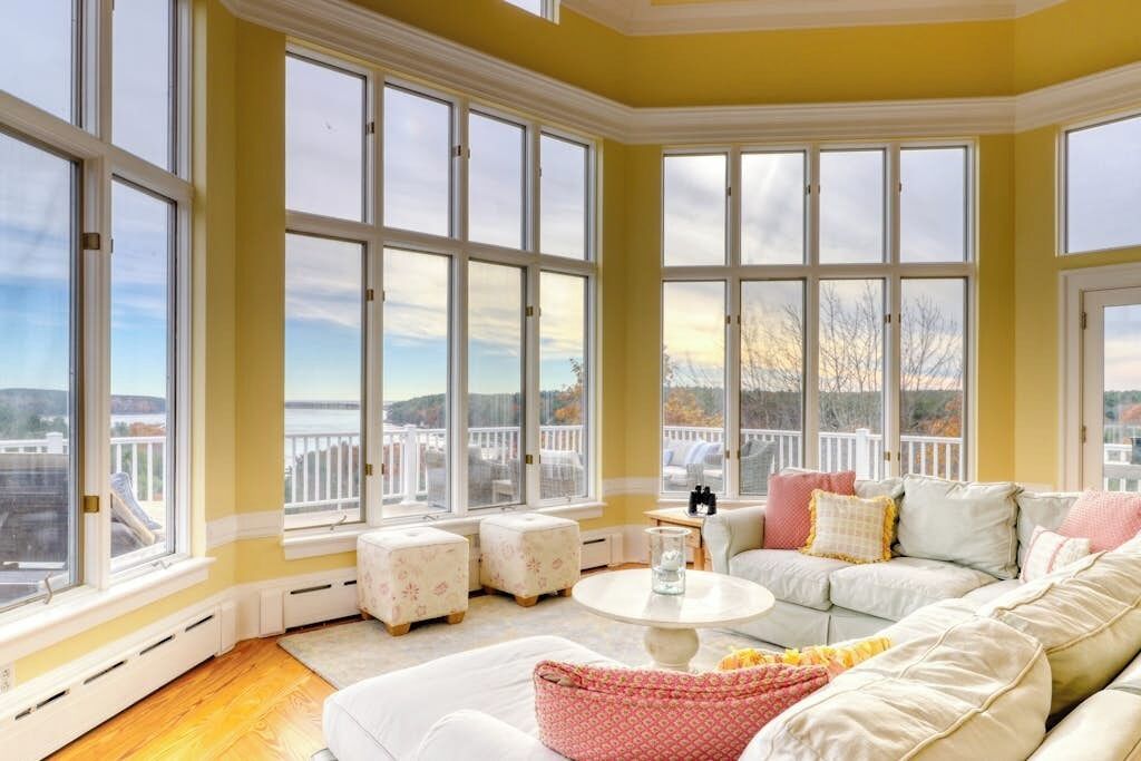 A room with large windows, a white sofa, and a view of a waterfront.