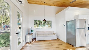 A modern kitchen with a large refrigerator, a wooden ceiling, and a window with a view of greenery. - Modern Maine Cottage With River Views, Deck, and a Convenient Washer/dryer (Stockton Springs)