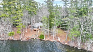 A cabin surrounded by trees, a dock, and a body of water. - Lakefront House on Damariscotta Lake, Perfect Getaway (Nobleboro)