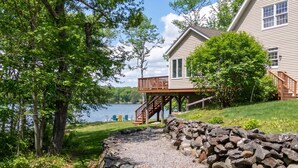 Une propriété située au bord du lac, dotée d’un mur en pierre, d’une terrasse en bois et offrant une vue sur le lac.
