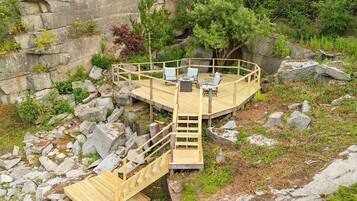 Une terrasse en bois avec un escalier menant à un espace de détente circulaire, comprenant des chaises et une table.