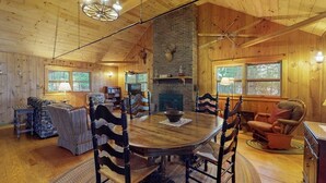A wooden cabin interior with a dining table, chairs, a fireplace, and a cozy seating area. - Lakefront Home With Private Dock, Pebble Beach & Enclosed Porch - Dogs Welcome (Greenville)