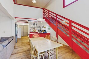 A modern interior with a dining area, kitchen, and staircase. - Summertime (Bar Harbor)