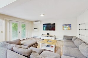 A modern living room with a sofa set, a coffee table, a flat-screen TV, and a painting on the wall. - Summertime (Bar Harbor)