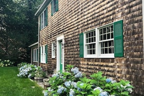 Ein Holthaus mit grünen Fensterläden und einer weißen Tür.